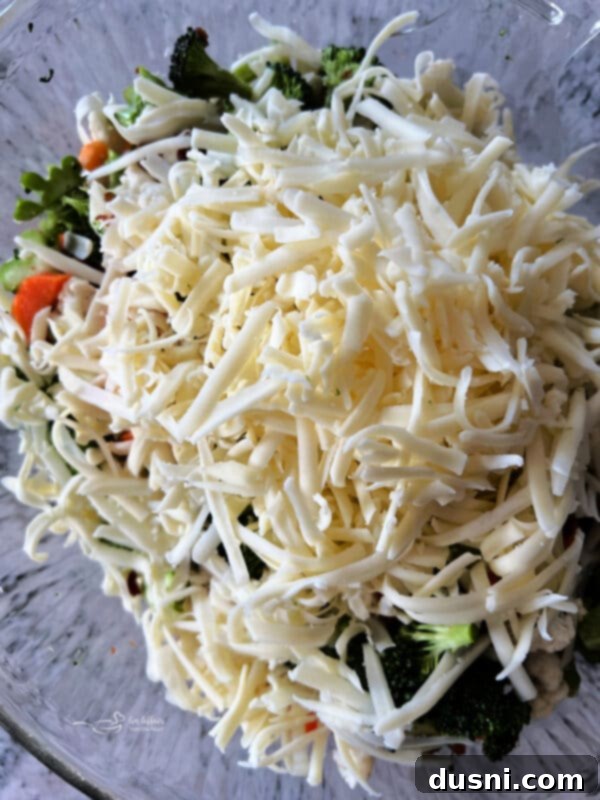 Vibrant Italian Garden Salad 9 Shredded mozzarella cheese being added to the vegetable and bacon mixture.