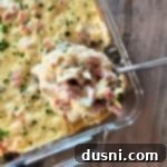 Scooping the Chicken Cordon Bleu Casserole with Rice out of a clear baking dish.