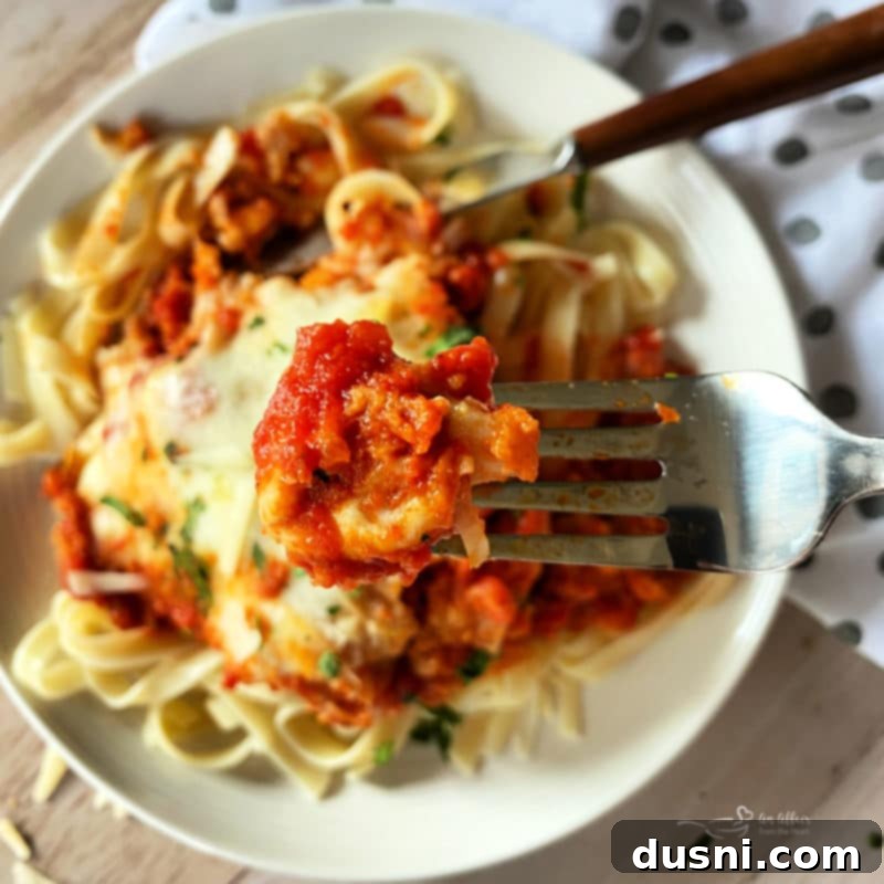 close view of chicken parmesan on fork over plate