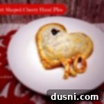 Cherry Sweetheart Pies 2 Heart shaped hand pie with pie crust piece XO on a white plate. Text "heart shaped cherry hand pies"