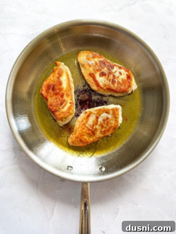 Creamy Chicken and Mushroom Florentine Pasta 11 Flipped chicken breasts continuing to cook in the skillet.