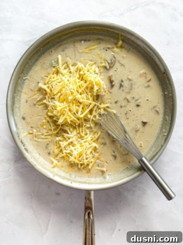 Creamy Chicken and Mushroom Florentine Pasta 13 Ingredients for the sauce (flour, cream, chicken stock, salt, pepper) being whisked in a bowl.