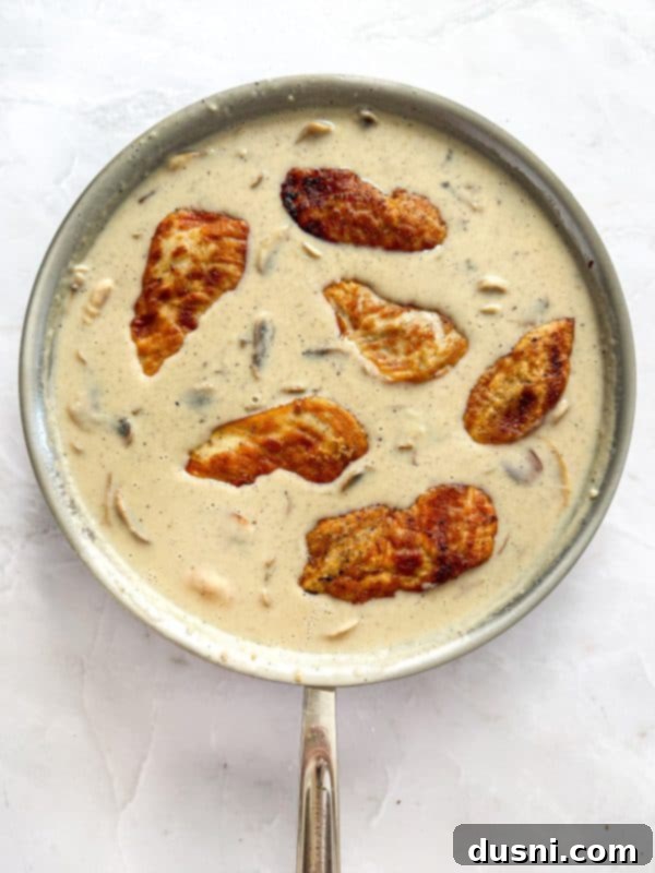 Creamy Chicken and Mushroom Florentine Pasta 14 Gouda cheese being whisked into the creamy mushroom sauce in the skillet.