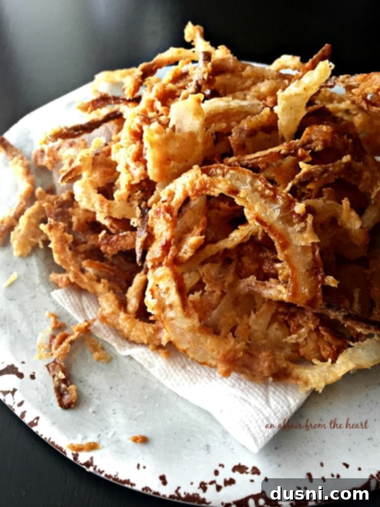 Crispy Golden Onion Strings 5 A bowl of fresh, hot homemade onion strings arranged beautifully on a light blue plate, ready to be served.