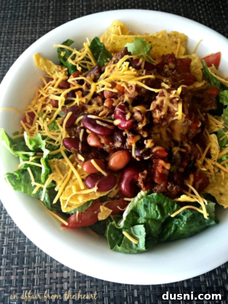 Close-up of a Copy Cat Wendy's Original Taco Salad, showing the layered ingredients: chili, cheese, and fresh greens.