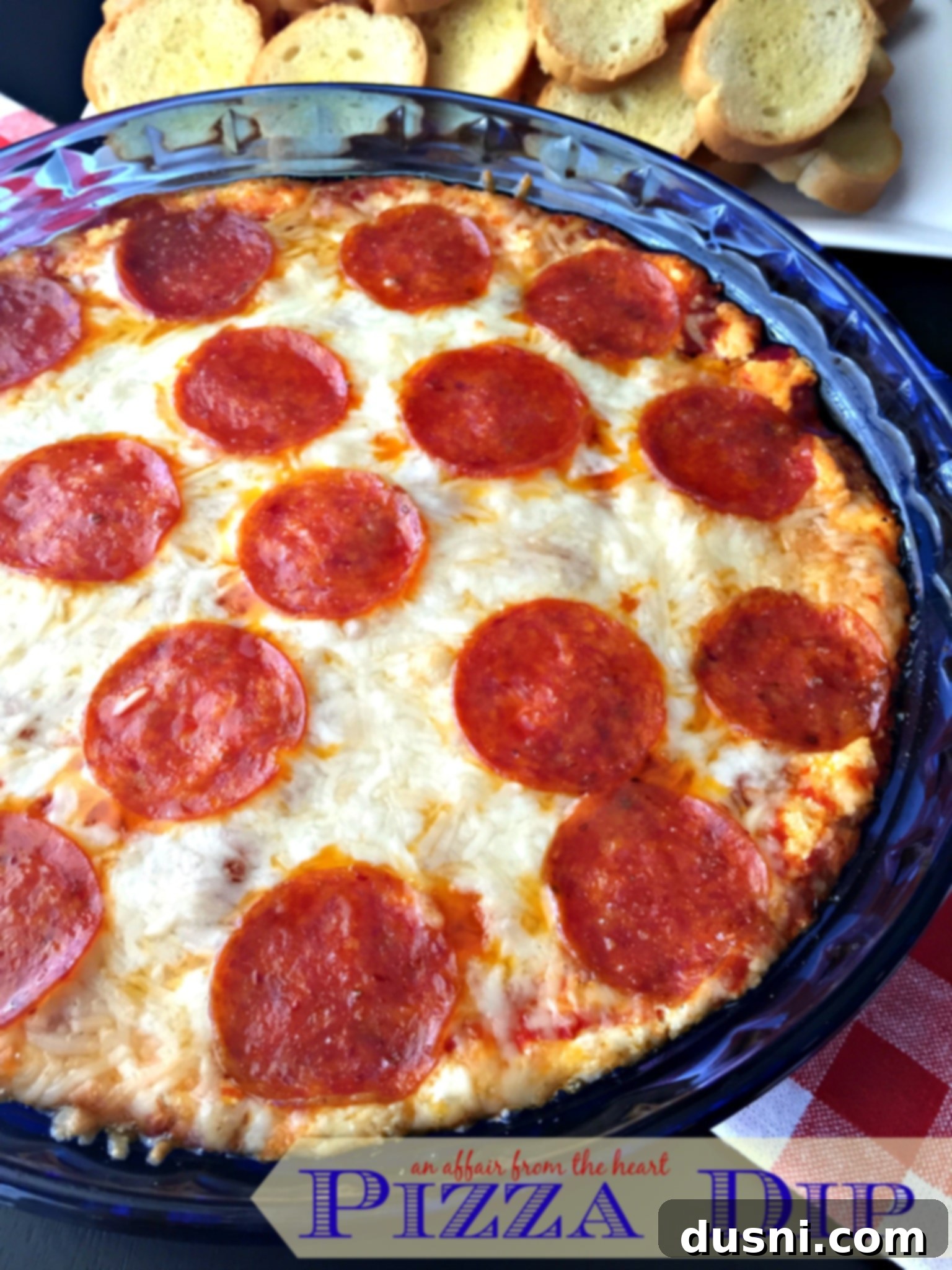 Warm Cheesy Pizza Dip in a baking dish with garlic toasts, ready to be served