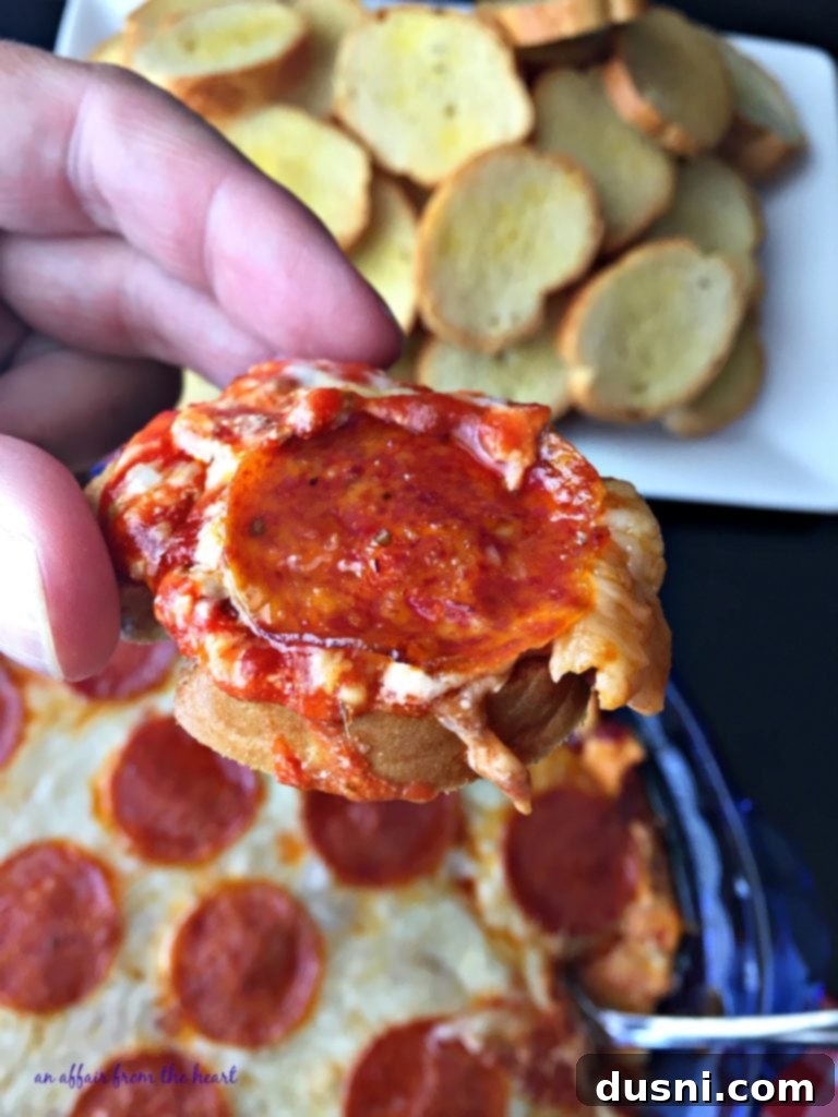 Pizza Dip being scooped, showing layers of cheese and pepperoni