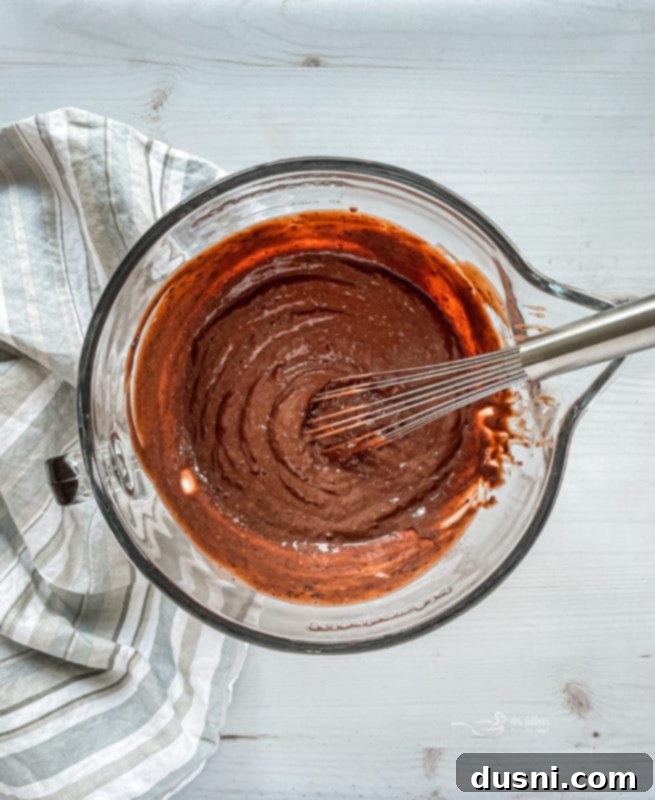 Ultimate Chocolate Pudding Dream Cake 7 Chocolate pudding being whisked in a bowl for the poke cake.