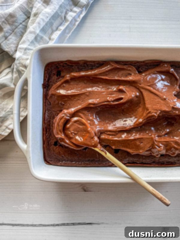 Ultimate Chocolate Pudding Dream Cake 8 Poking holes into a warm chocolate cake with the handle of a wooden spoon.