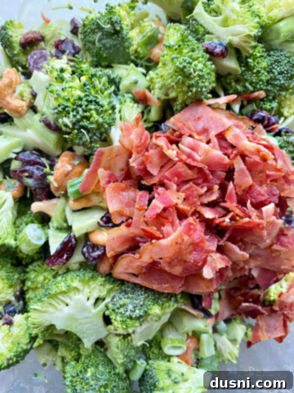 Smoky Cashew Broccoli Crunch 10 Top view of broccoli salad with bacon, showing the final mix of ingredients and the rich dressing.
