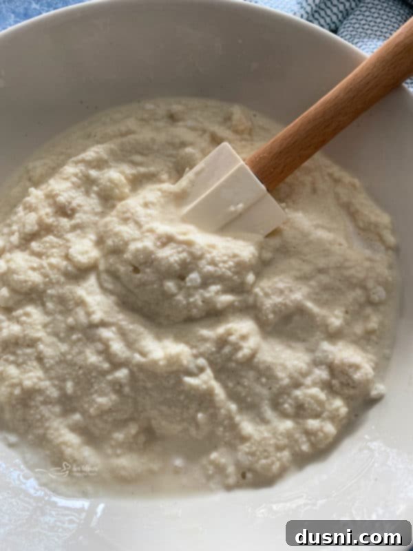 Hands stirring the snow and sweetened condensed milk in a large bowl, showing the initial mixing process.