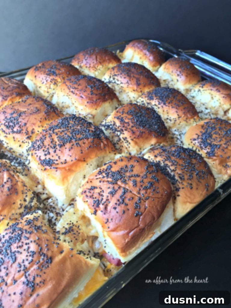 Baked Roast Beef Sliders with Horseradish Sauce on a wooden board.