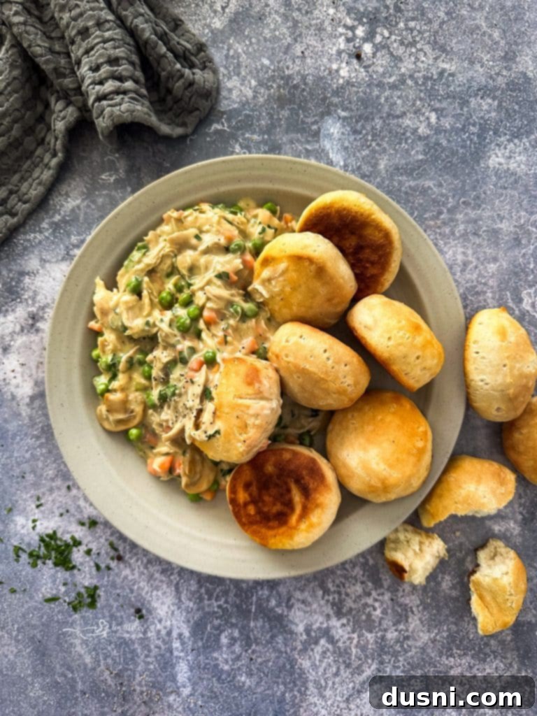 Creamy Chicken à la King served over fluffy biscuits, garnished with fresh parsley.