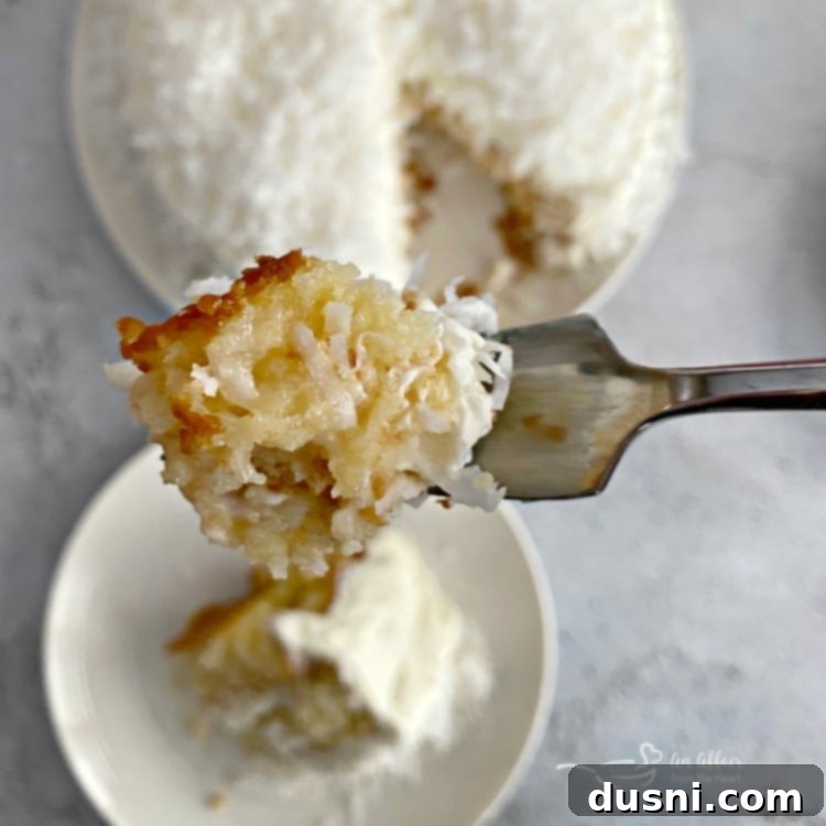Close-up of a single bite of Coconut Cream Poke Cake on a fork, showing its moist texture.