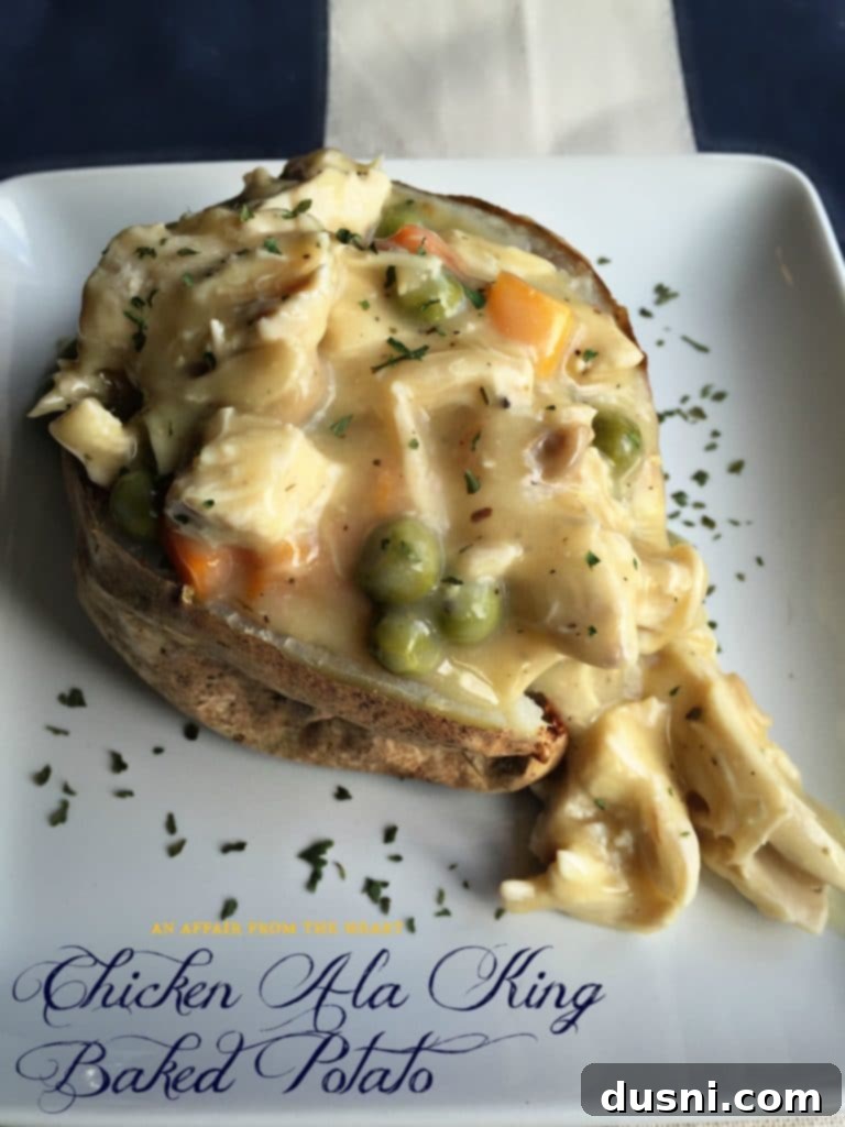 A perfectly baked potato generously stuffed with creamy Chicken à la King, garnished with fresh herbs