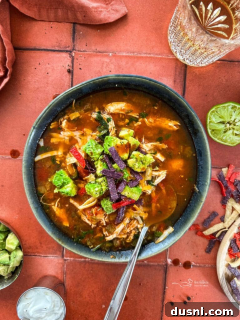 A bowl of Slow Cooker Chicken Enchilada Soup garnished with fresh cilantro and a lime wedge