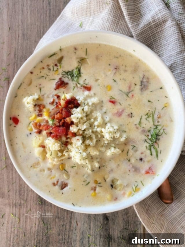 A hearty bowl of Cheesy Potato Corn Chowder with a spoon and napkin