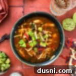 Close up of slow cooker Enchilada soup topped with avocado and tortilla strips.