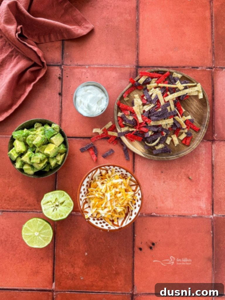 A selection of fresh toppings for chicken enchilada soup including shredded cheese, avocado, and sour cream