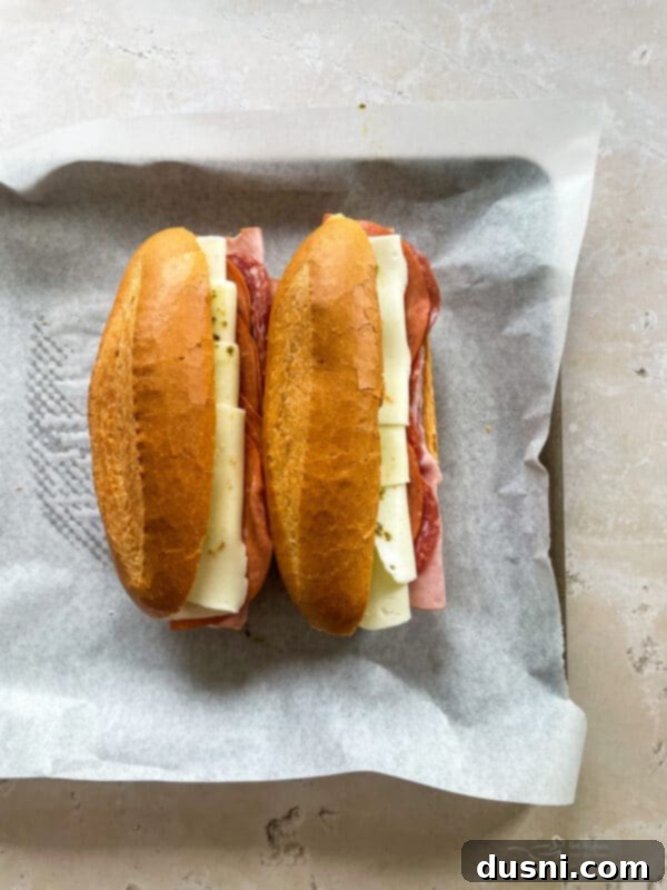 Crispy Italian Sub Melts 6 Assembled Italian Sub sandwiches on a baking sheet, ready for the oven