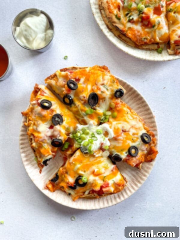Close-up of two homemade Taco Bell Mexican Pizzas, garnished with diced tomatoes and green onions.