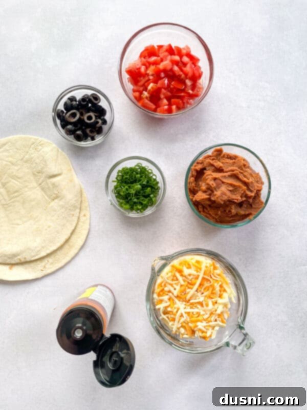 Fresh toppings for homemade Mexican Pizza: refried beans, salsa, tortillas, cheese, green onions, tomatoes, and black olives.