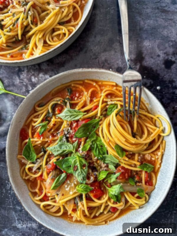 A close-up shot of a steaming bowl of Italian Wonderpot Pasta, garnished with fresh basil leaves and grated Parmesan cheese.