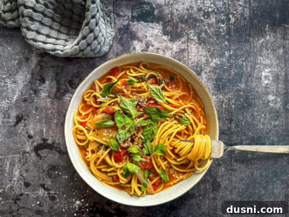 A close-up of the cooked Italian Wonderpot Pasta, showing spinach, tomatoes, and pasta strands intertwined.