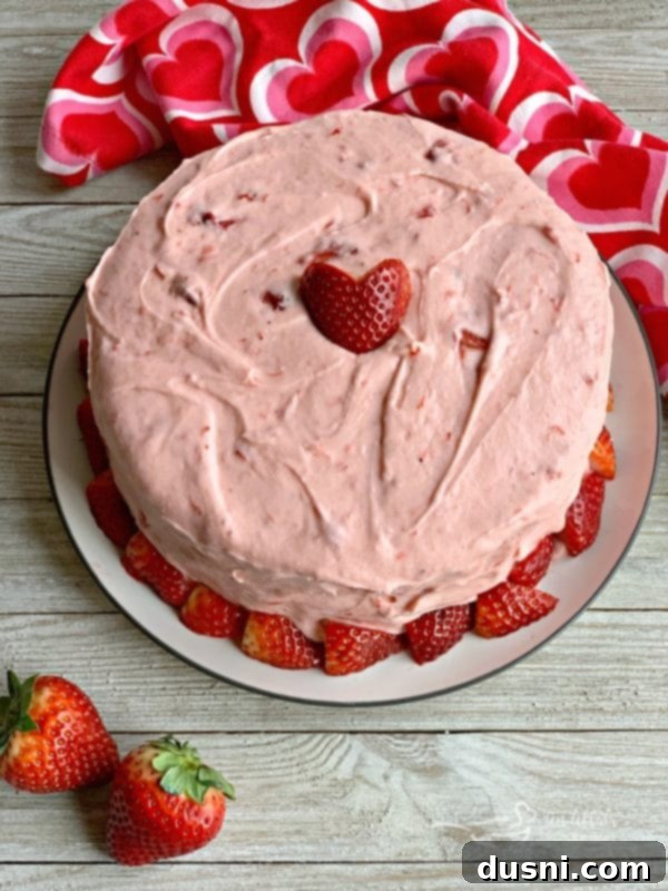 Beautifully layered Strawberry Cake with vibrant pink frosting and fresh strawberries, a festive and delicious dessert for Valentine's Day celebrations.