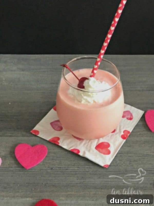 A vibrant pink Pink Squirrel Cocktail, garnished with whipped cream and a maraschino cherry, perfect for a romantic Valentine's Day drink.