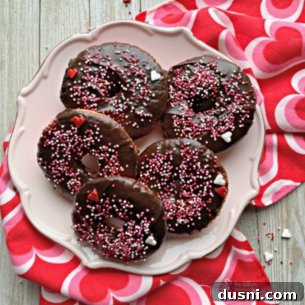 Delicious Baked Chocolate Covered Strawberry Donuts, heart-shaped and decorated with pink frosting, perfect for a Valentine's Day breakfast in bed.