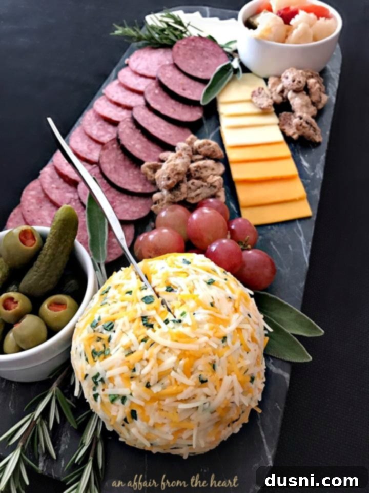 The Ultimate Summer Sausage Cheese Ball 16 Finished Summer Sausage Cheese Ball displayed on a cheeseboard with crackers and other accompaniments.