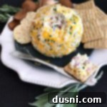 The Ultimate Summer Sausage Cheese Ball 18 Summer Sausage Cheese Ball and crackers on a white serving plate, garnished with fresh herbs.