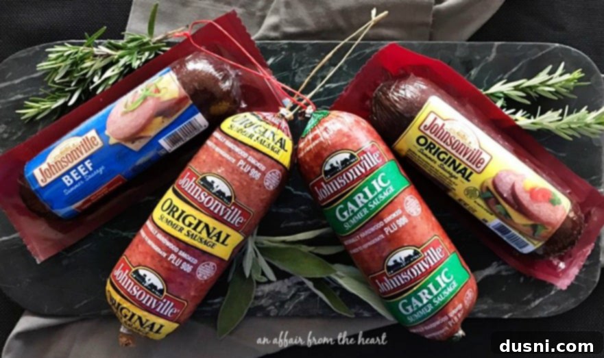 The Ultimate Summer Sausage Cheese Ball 4 Assortment of Johnsonville Summer Sausage, cheeses, and grapes on a wooden serving board.