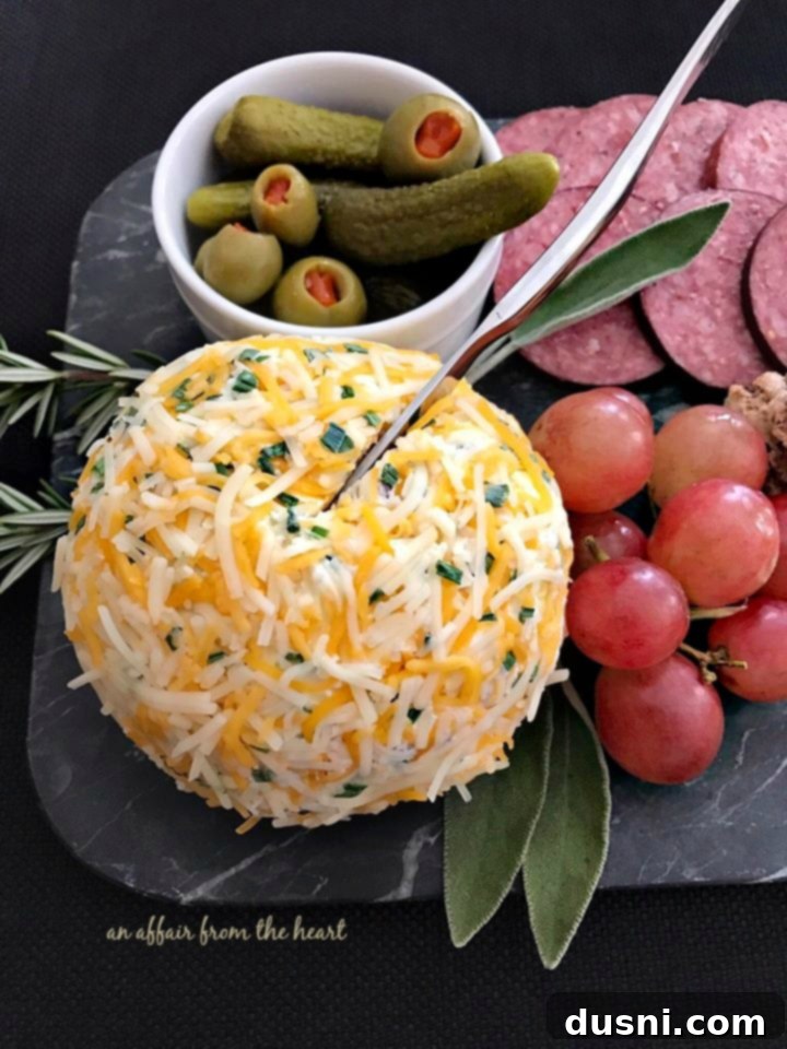 The Ultimate Summer Sausage Cheese Ball 5 Close-up of a Johnsonville Summer Sausage Cheese Ball on a festive cheeseboard with crackers and grapes.