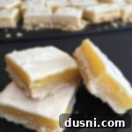 Zesty Glazed Lemon Squares 10 Glazed Lemon Bars stacked on a black napkin