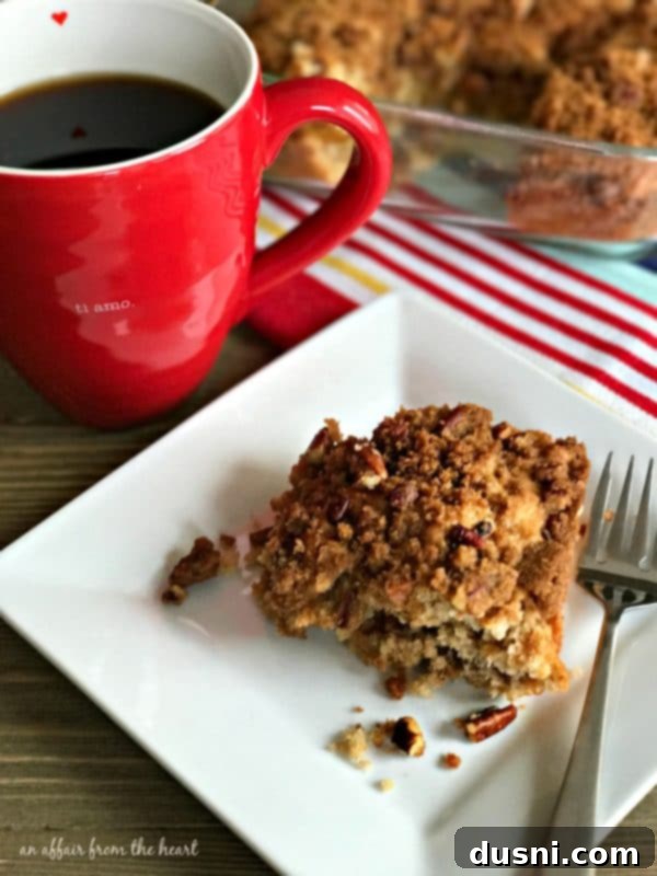 Golden Cinnamon Streusel Coffee Cake 2 A slice of Cinnamon Crunch Coffee Cake on a white plate with a fork, showing the distinct layers of cake and the crunchy topping.