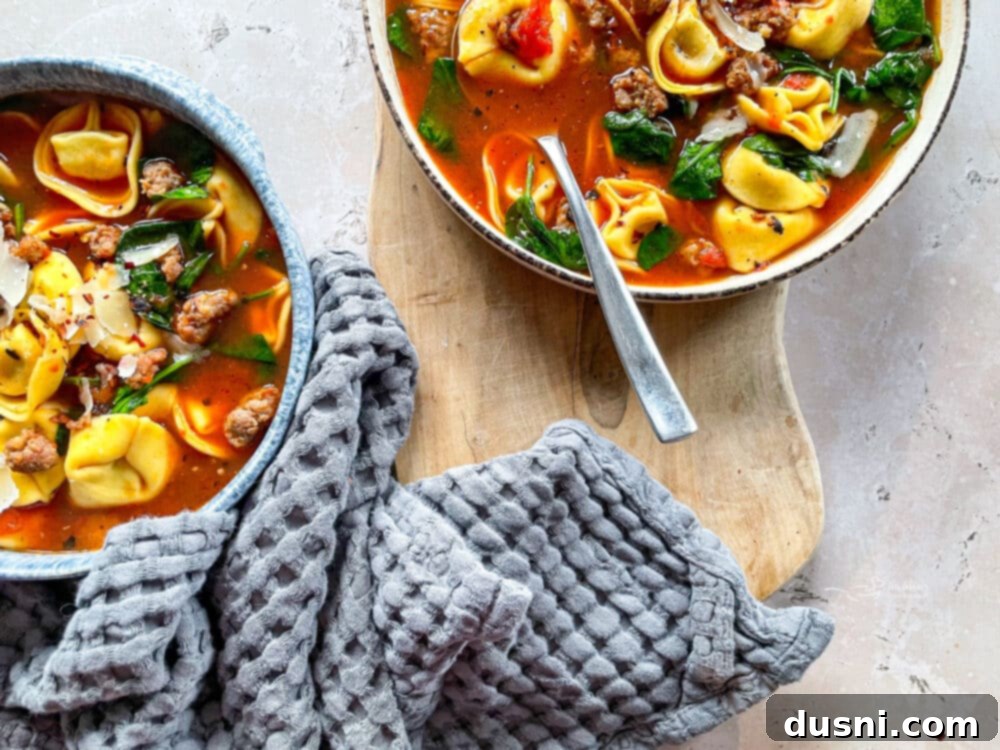 Bowl of tortellini soup with a rustic wooden spoon