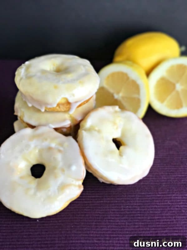 Close-up of baked glazed lemon donuts, one with a bite taken out, on a wire rack