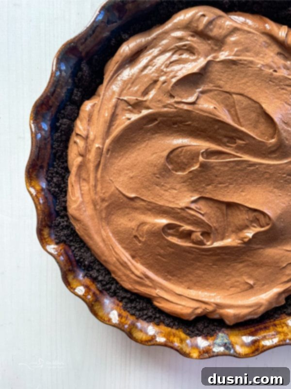 Top view of the chocolate filling in the pie crust, covered with plastic wrap, chilling in the refrigerator.