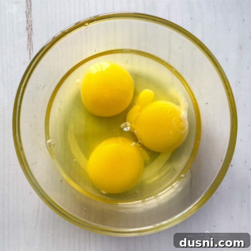 Three fresh eggs carefully placed in a mixing bowl, ready for the French Silk Pie filling.