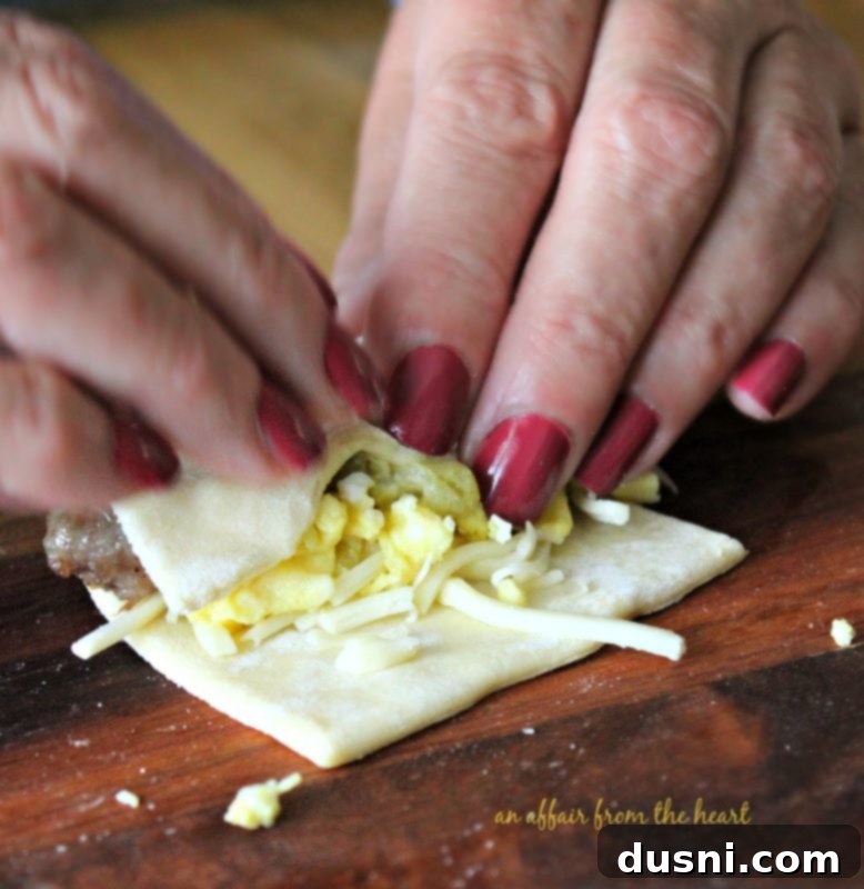 Filling a puff pastry square with sausage, egg, and cheese