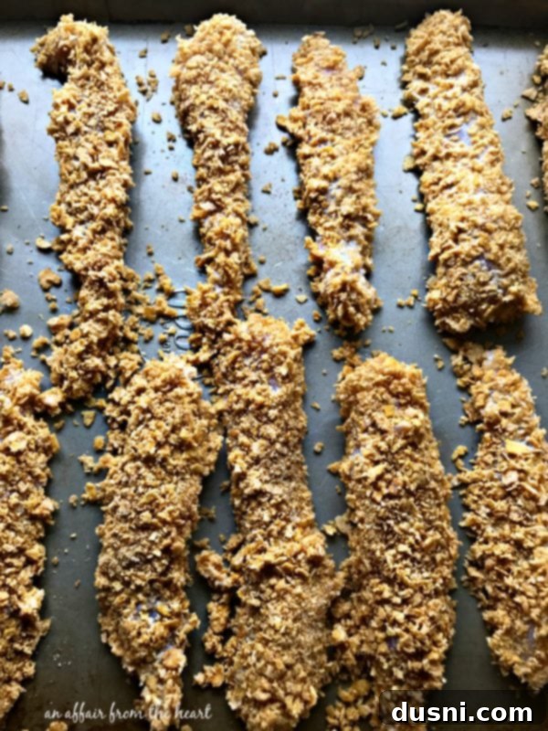 Zesty Oven-Baked Chicken Strips 12 Chicken tenderloin being coated in crushed corn flake cereal and spices.
