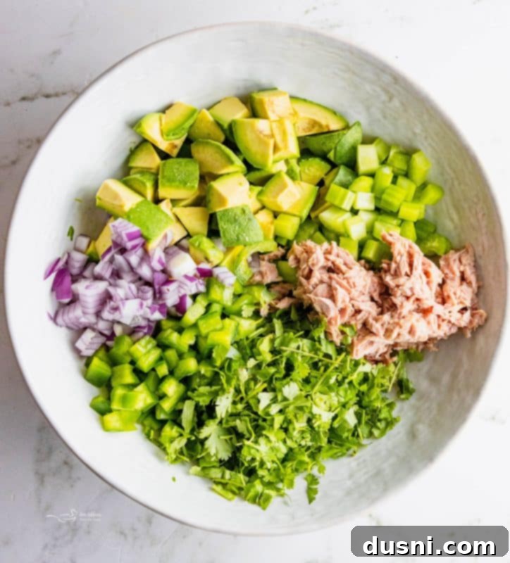 Creamy Avocado Tuna Bliss 5 All the fresh ingredients for Avocado Tuna Salad laid out on a wooden cutting board.