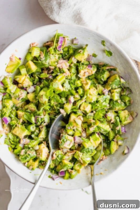 Creamy Avocado Tuna Bliss 9 A bowl of Avocado Tuna Salad with a fork, ready to be enjoyed.