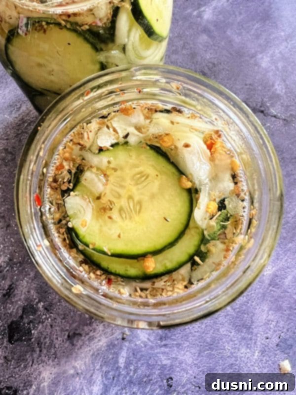 Sweet and Spicy Refrigerator Pickles in a mason jar, garnished with fresh herbs