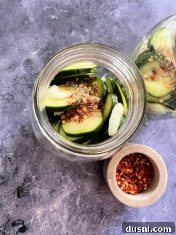Step-by-step image of pouring hot brine over cucumbers and onions in a mason jar