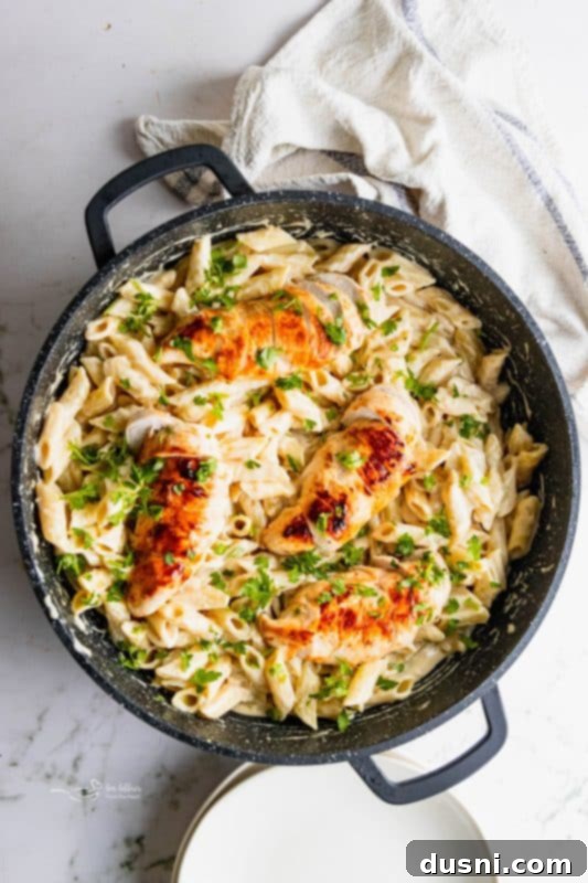 A close-up shot of a steaming bowl of Creamy Chicken Penne Pasta garnished with fresh parsley.