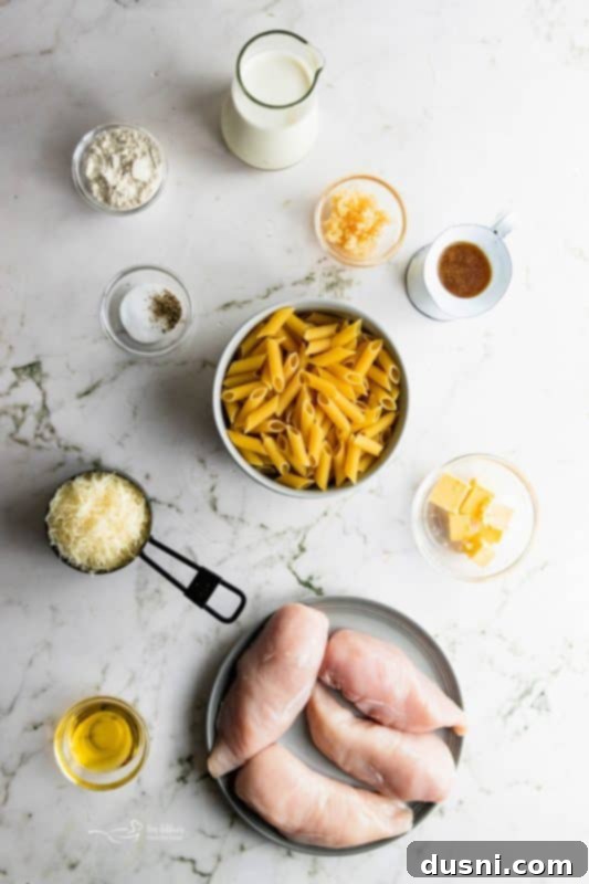 A close-up of a serving of Creamy Chicken Penne Pasta on a white plate, showing the creamy sauce and chicken pieces.