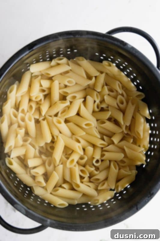Cooked penne pasta in a colander, freshly drained.